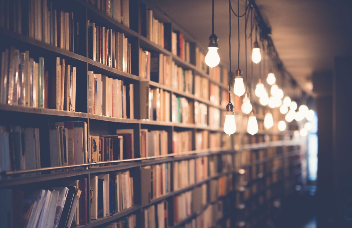 A photograph of a library illuminated with hanging light bulbs.