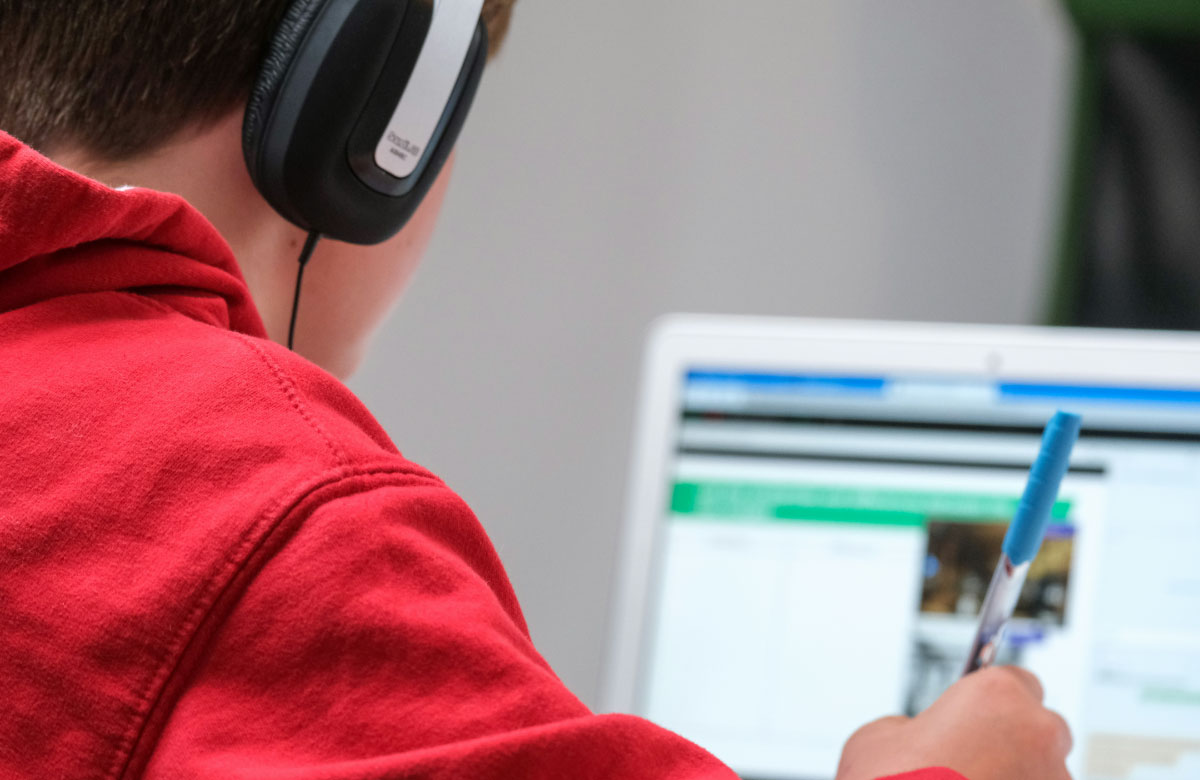 A photograph of a learner working on an online course and taking notes.