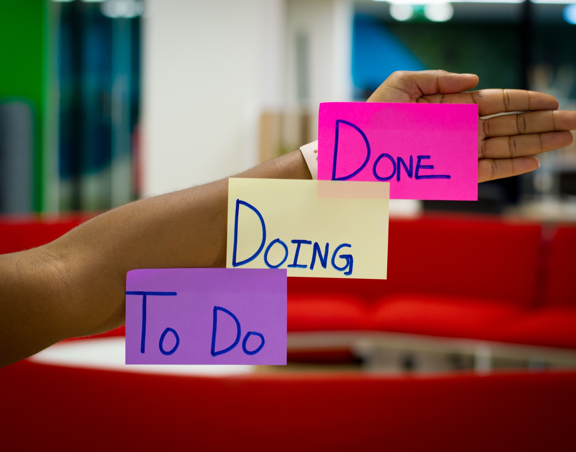Image of a woman's arm extended, with three sticky notes reading, in order, 'To Do', 'Doing', and 'Done.'